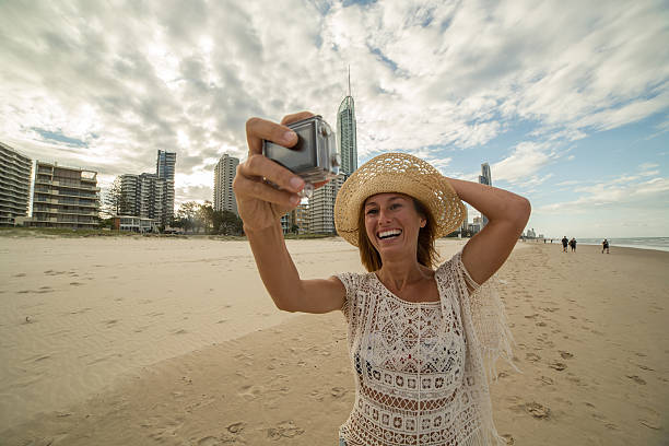サーファーの楽園の女の子は、アクションカメラを使用して自分撮り肖像画を取ります - australia photographing camera beach ストックフォトと画像