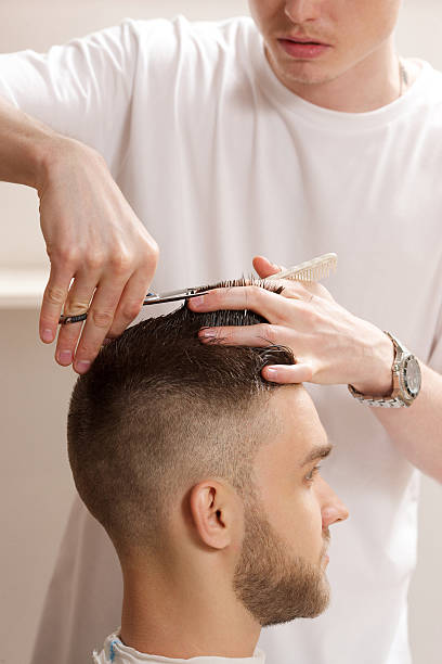 istock barber cuts hair with scissors 588958772