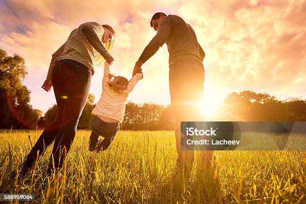 Parents Hold Babys Hands Happy Family In Park Evening Stock Photo - Download Image Now
