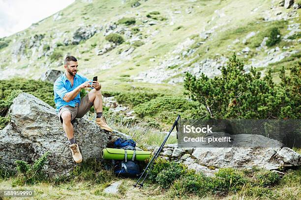 Solo Traveler Texting On A Rock Stock Photo - Download Image Now - Footpath, Remote Location, Hiking
