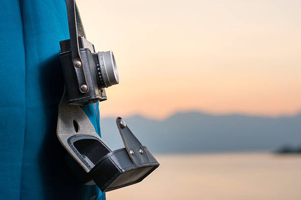 Vintage camera hanging from womans shoulder by the lake
