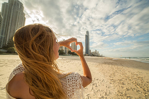 istock Young woman frames Surfers paradise beach into heart shape 588960606