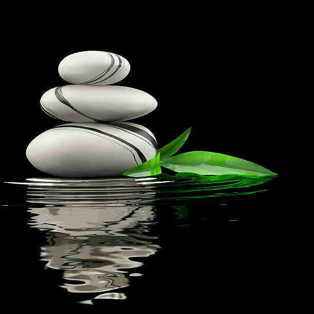Spa stones and bamboo leaf in waters on black background.