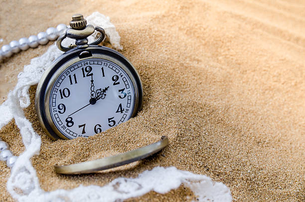 istock Vintage pocket watch with perfume on sand background 588966322