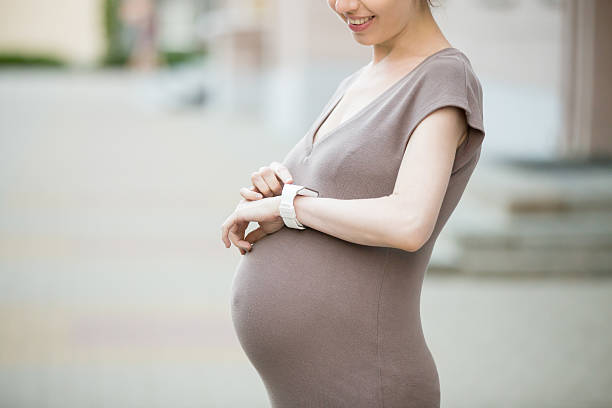 schwangere frau mit smart-uhr. nahaufnahme - checking the time watch women looking stock-fotos und bilder