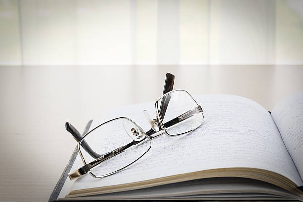istock Eyeglasses put on a book with on the desk 588968390