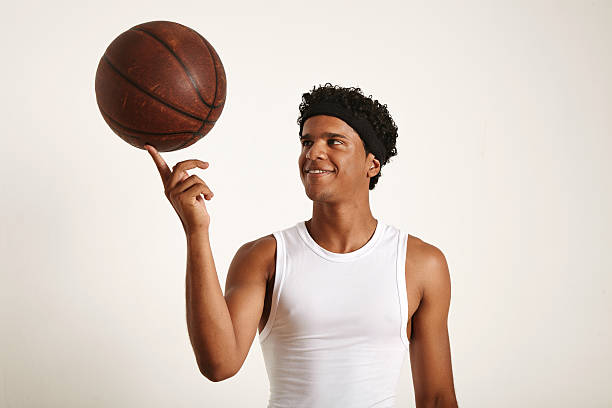 istock Young black athlete balancing leather basketball on finger 588969070