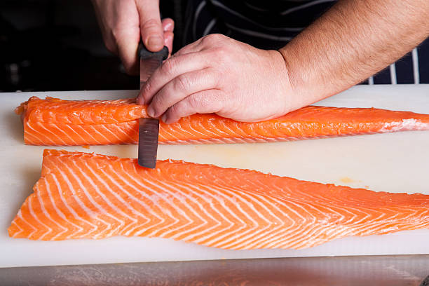istock Chef cutting salmon fish on fillets with knife 588970490