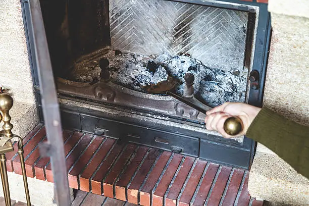 Cleaning the fireplace. Hand of man holding a brass shovel with ash