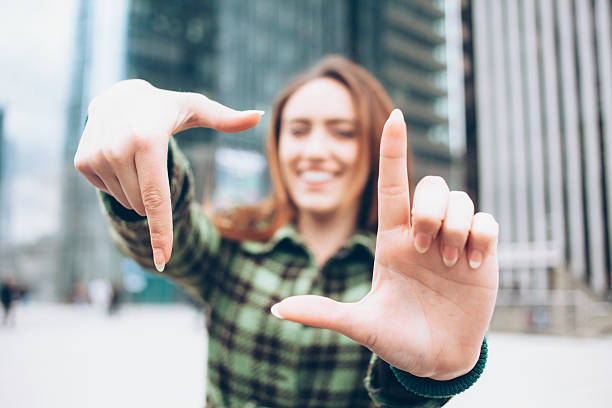 istock Smiling young woman looking through finger frame 588972590