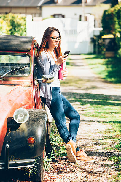 istock Young woman leaning on a car and using smart phone 588972828