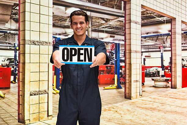 istock Smiling mechanic holding open sign 588977136