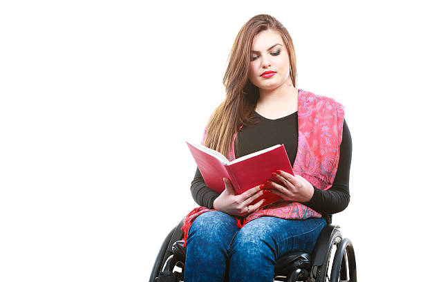 istock Young disabled woman in wheelchair with book. 588977604
