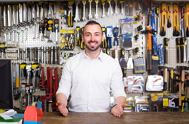 portrait of cheerful man at the cash desk working portrait of young cheerful european man at the cash desk working in tool-ware shop market vendor stock pictures, royalty-free photos & images