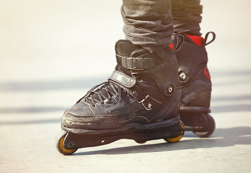 Aggressive inline skates on rollerblader feet. Extreme sports athlete in concrete outdoor skate park. Focus on roller blades, professional model for tricks and grinds