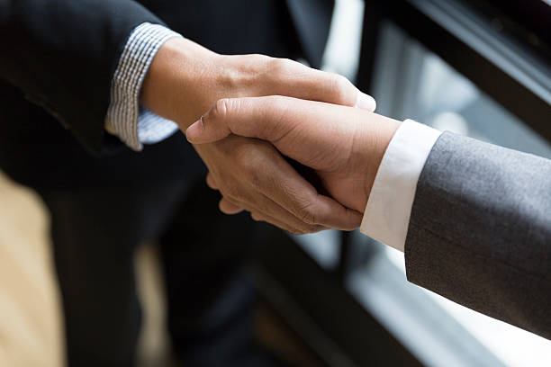 istock businessmen in suit shaking hands beside window - 588982782