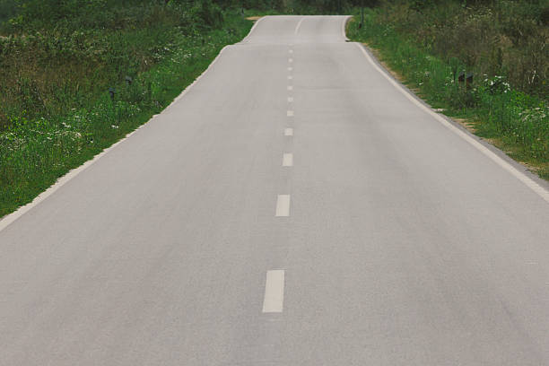 istock Straight asphalt road across countryside 588983060