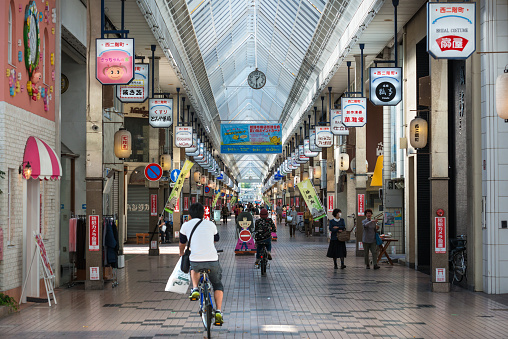 Himeji, Japan - October 7, 2015: Wide-angle view of the Miyuki-dori shopping arcade in Himeji with some early local shoppers on foot and by bicycle, Japan.