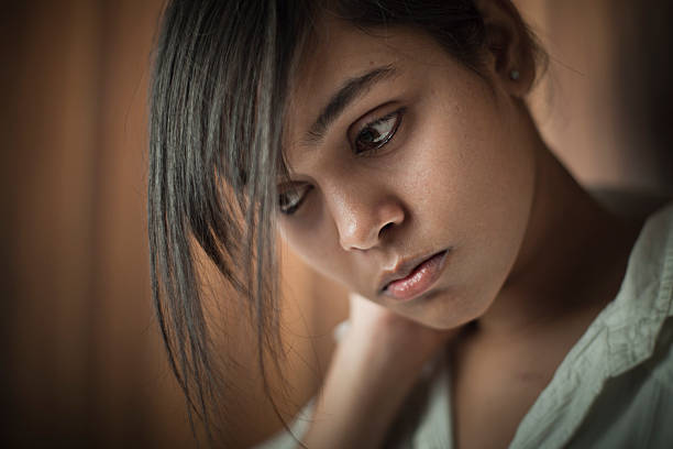 Serene Asian sad teenage girl looking down and thinking. stock photo