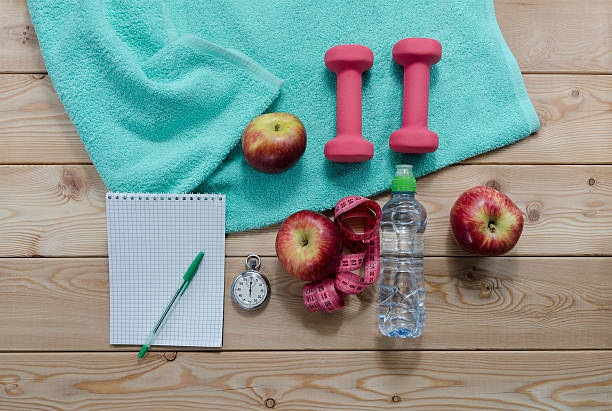 . dumbbells bottle of water measure tape fruit and notepad.