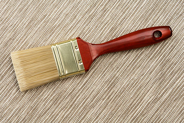 Wall paint brush on beige thatch stock photo