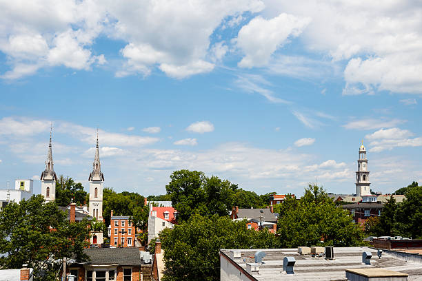 Steeples, spires and rooftops in a small town.  Blue cloud filled sky adds to the quaintness of the scene.