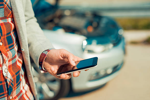 Man using smartphone after traffic accident Man with a silver car that broke down on the road.He is waiting for the technician to arrive. insurance agent photos stock pictures, royalty-free photos & images