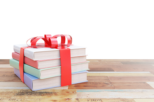Aged wooden surface with stack of colorful books tied up with a ribbon as a present on white  background. 3D Rendering
