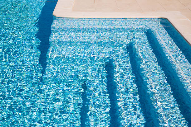 swimming pool steps Swimming pool steps in the morning sunlight with shadows accentuating their pleasant curved shapes. The steps are tiles with tiles of various shades of blue. shades of blue stock pictures, royalty-free photos & images