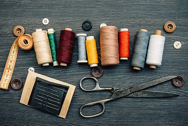 Equipment in the tailor shop, thread, sweing needle and scissors, buttons and fashion design plans. swing threads in row