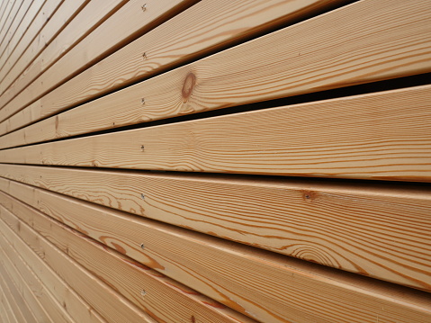 Background texture of finely slatted natural brown wood in a parallel pattern used in building decor and construction