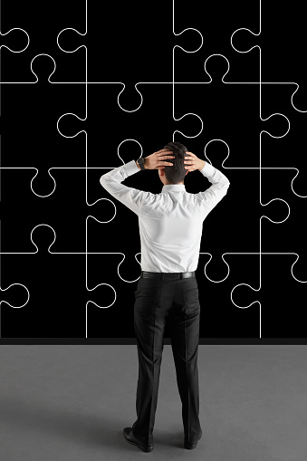 Businessman looking at puzzle pieces on the wall