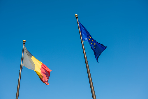 Belgian and European Union flags against blue sky
