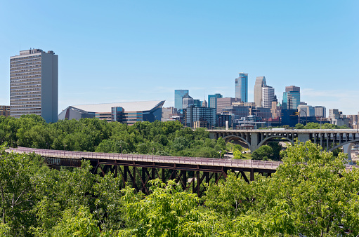 skyline of downtown minneapolis with tenth avenue and pedestrian bridge spanning mississippi river from east river road