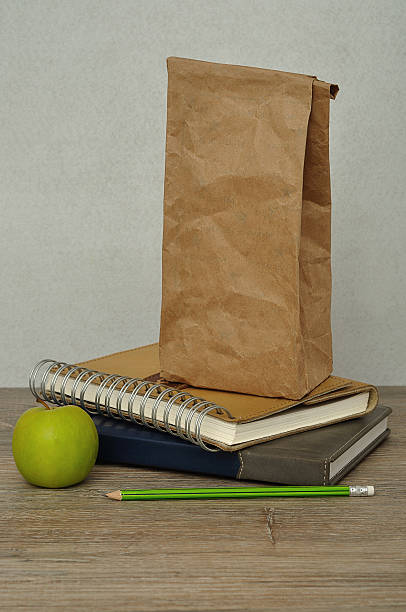istock Green apple. a paper lunch bag and books 589091912