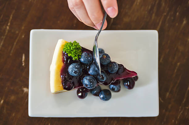 Blueberry cheesecake on white dish with hand