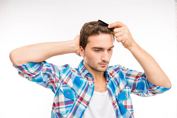 istock Calm young man combing his hair 589094232