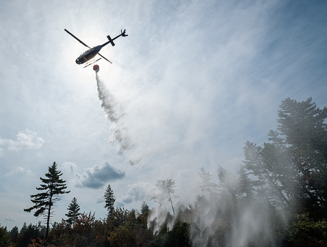 A helicopter pilot makes a water drop on a hot spot in forest fire.