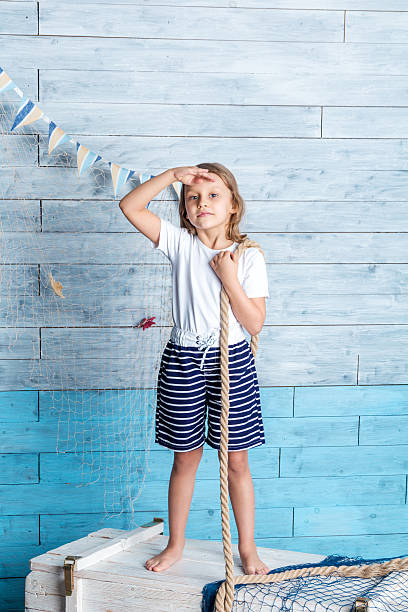 istock Little girl sailor standing and keeps rope 589097652
