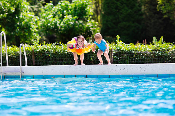istock Little kids jumping into swimming pool 589100702