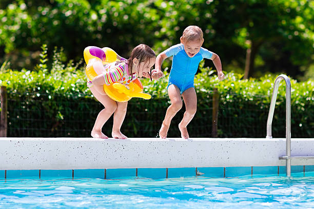 istock Girl and boy jumping into swimming pool 589102702