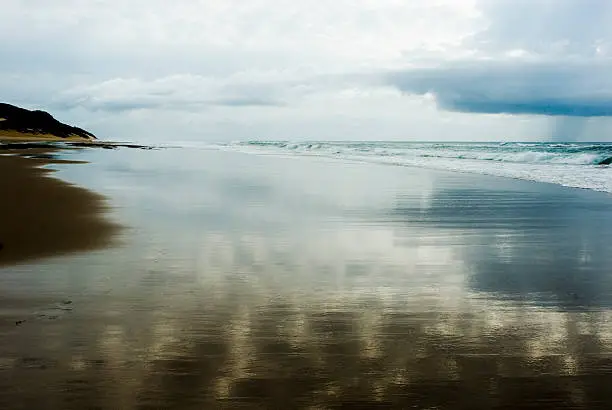 The wet sand along South Africa's eastern coastal shoreline of Maputaland, KwaZulu-Natal, reflections and a lone cloud burst out over the deep Indian ocean is an enchanting sight. 