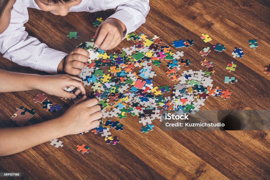 Happy boy and girl collect puzzle lying on the floor Happy boy and girl collect puzzle lying on the floor closeup Jigsaw Puzzle Stock Photo