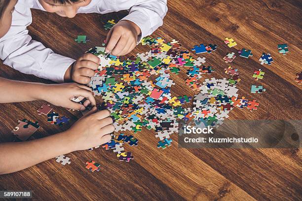 Happy Boy And Girl Collect Puzzle Lying On The Floor Stock Photo - Download Image Now