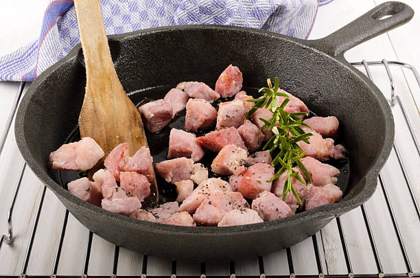 roasted bacon cubes with rosemary and sunflower oil in a cast iron pan