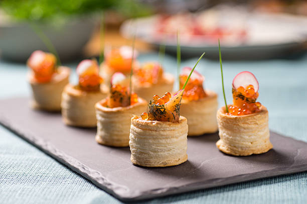 Delicious graved salmon appetizers Delicious appetizers with graved salmon and golden caviar served in puff pastry towers canape stock pictures, royalty-free photos & images