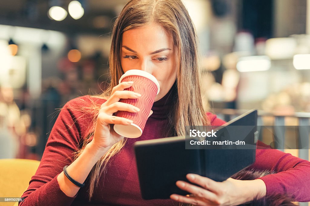 Woman at coffee break Young woman drinking coffee and reading an e-book 20-29 Years Stock Photo