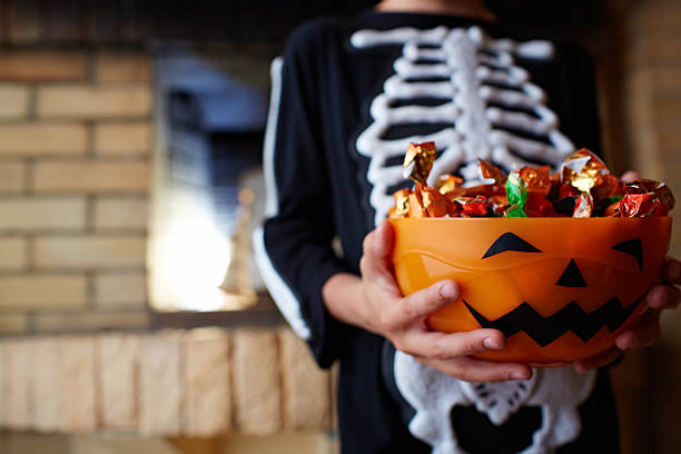 Halloween bowl with chocolate candies given by people stock photo