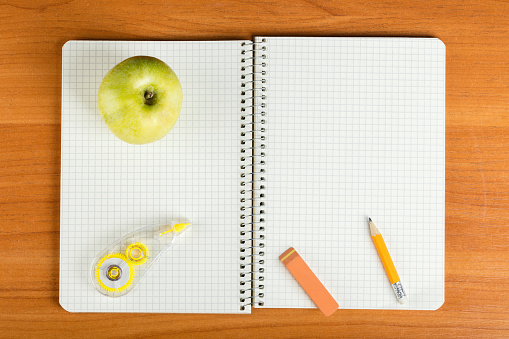 open notebook with stationery on wooden background