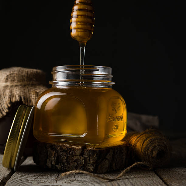 Golden honey in glass jar with dipper